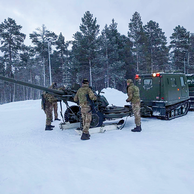 Soldiers from 29 Commando Regiment (UK) Royal Artillery attach skis to an artillery piece before it is towed behind a tracked over-the-snow-capable prime mover