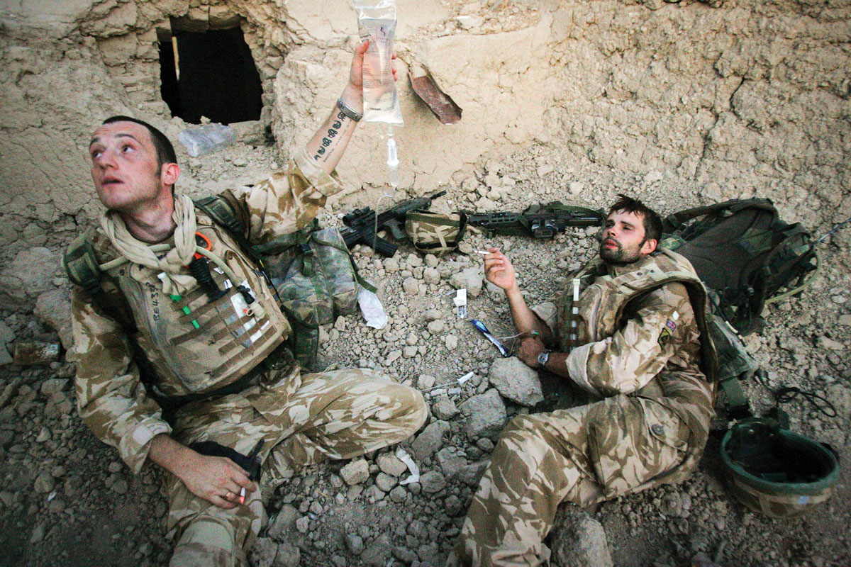 Lance Cpl. Andrew Howe of Company C, 1st Battalion, Royal Anglian, is given fluids intravenously by a combat medic as treatment for heat exhaustion in a ruined compound during a firefight with Taliban fighters in Kajaki, Helmand Province, Afghanistan, on 6 July 2007