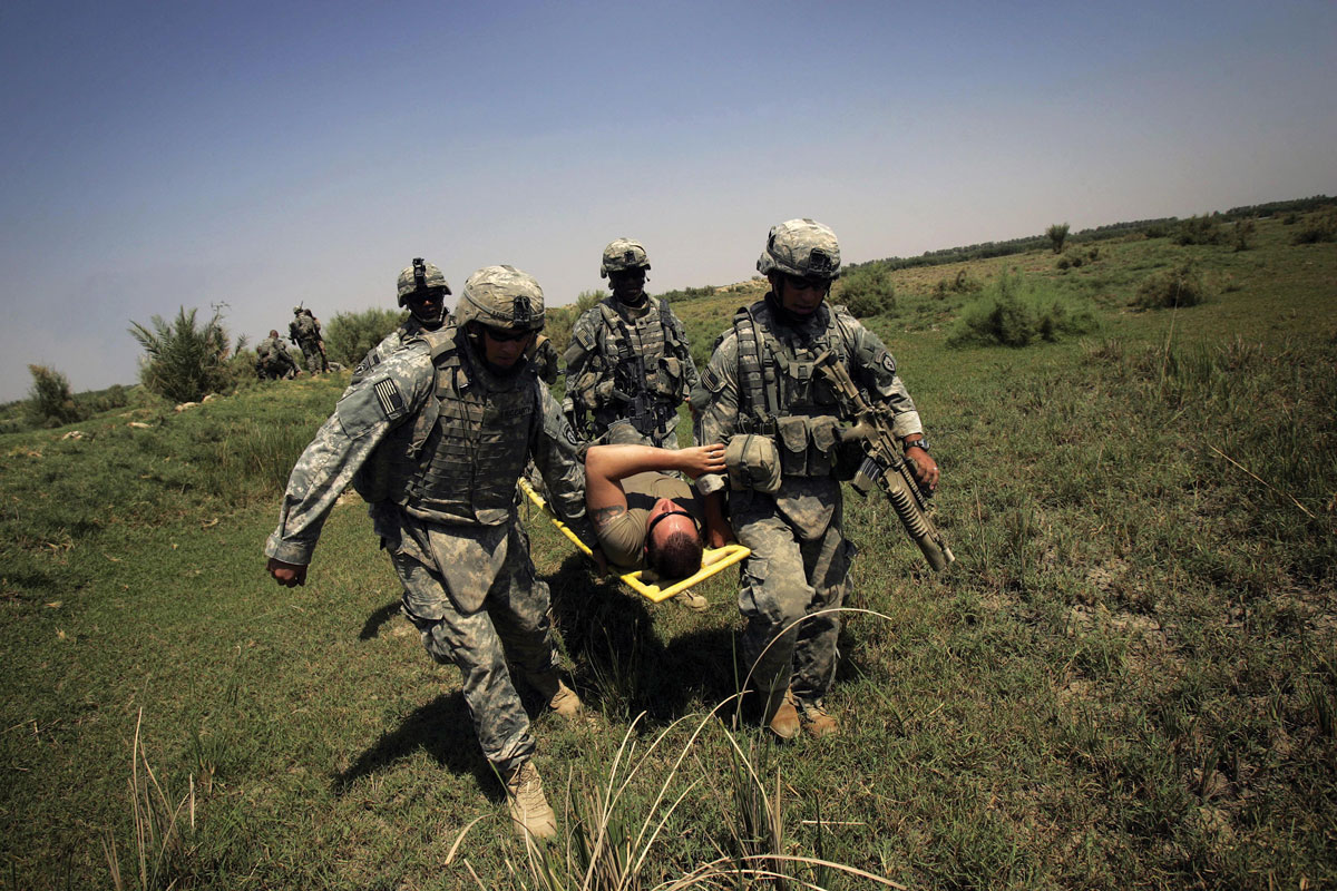 Soldiers from 1st Battalion, 501st Parachute Infantry Regiment, assist a fellow soldier who suffered heat stroke 24 August 2007 while conducting a foot patrol south of Baghdad during Operation Gecko.