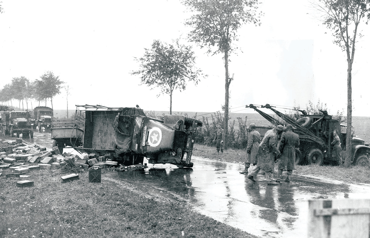 A road patrol wrecker (<em>right</em>) pulls an overturned truck back on its wheels circa 1944