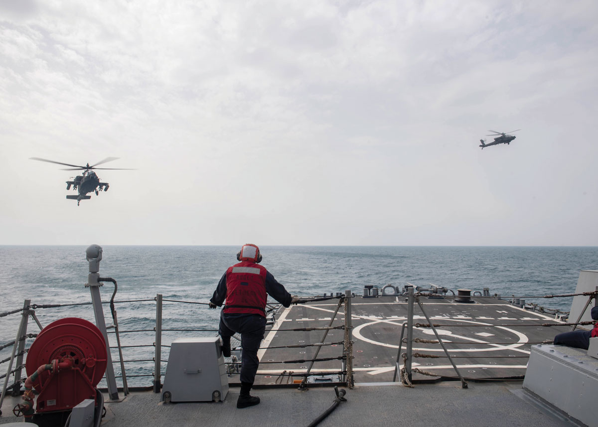 Two AH-64 Apache helicopters operate with the guided-missile destroyer USS Paul Hamilton