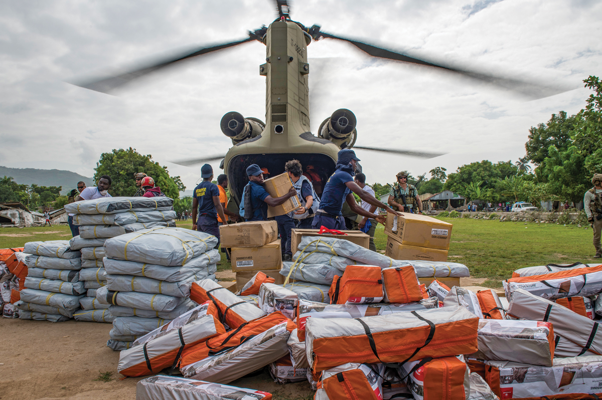 Members of Haiti’s Department of Civil Protection and an aircrew with the 1st Battalion, 228th Aviation Regiment, Joint Task Force-Bravo, out of Soto Cano Air Base, Honduras, deliver humanitarian aid supplies from a U.S. Army CH-47 Chinook 25 August 2021 to residents in Maniche, Haiti