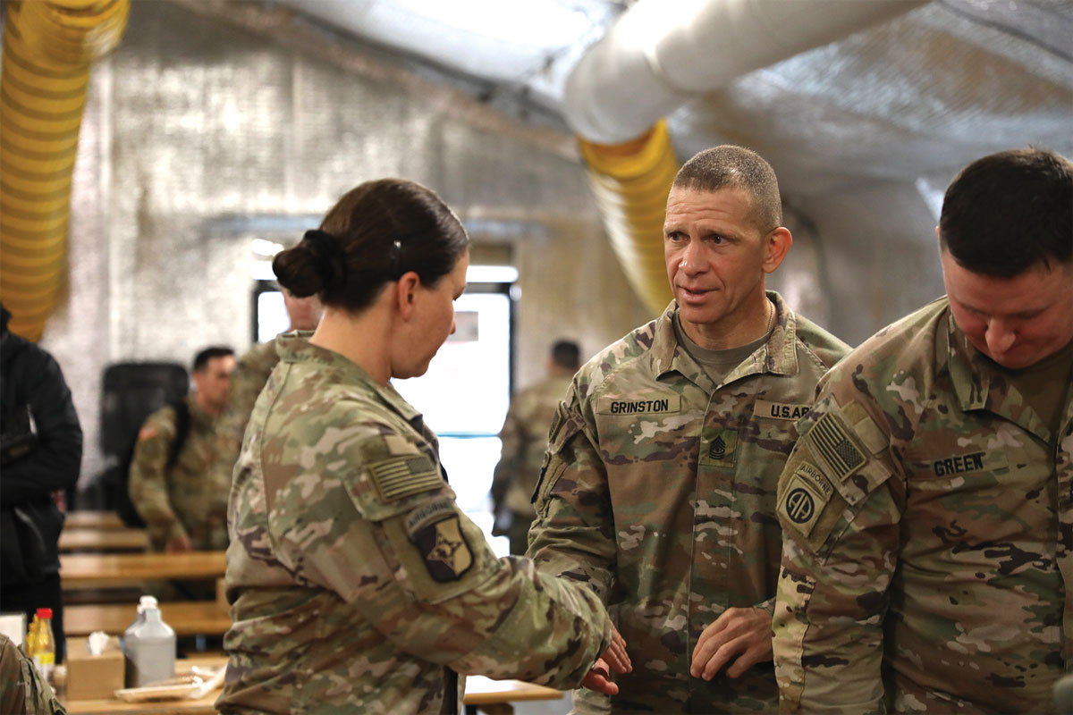 of the Army Michael A. Grinston presents Command Sgt. Maj. Vitalia Sanders, 101st Headquarters and Headquarters Battalion command sergeant major, with a coin after joining soldiers of the 101st Airborne Division