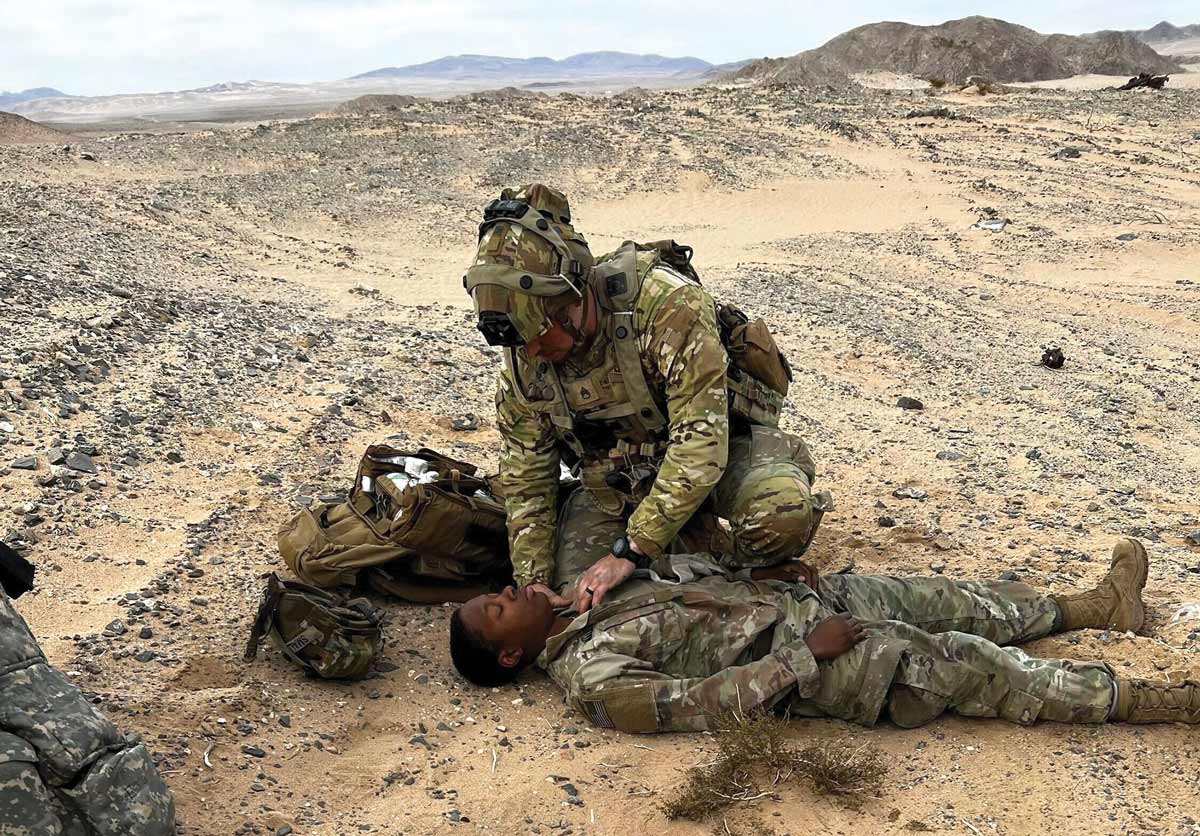 Staff Sgt. Bryant D. Pasko, the MAT 2112 medical advisor, treats Staff Sgt. Chaquetta Small, a wounded security force assistance brigade advisor, and prepares her for evacuation February 2023 during National Training Center rotation 23-04 at Fort Irwin, California