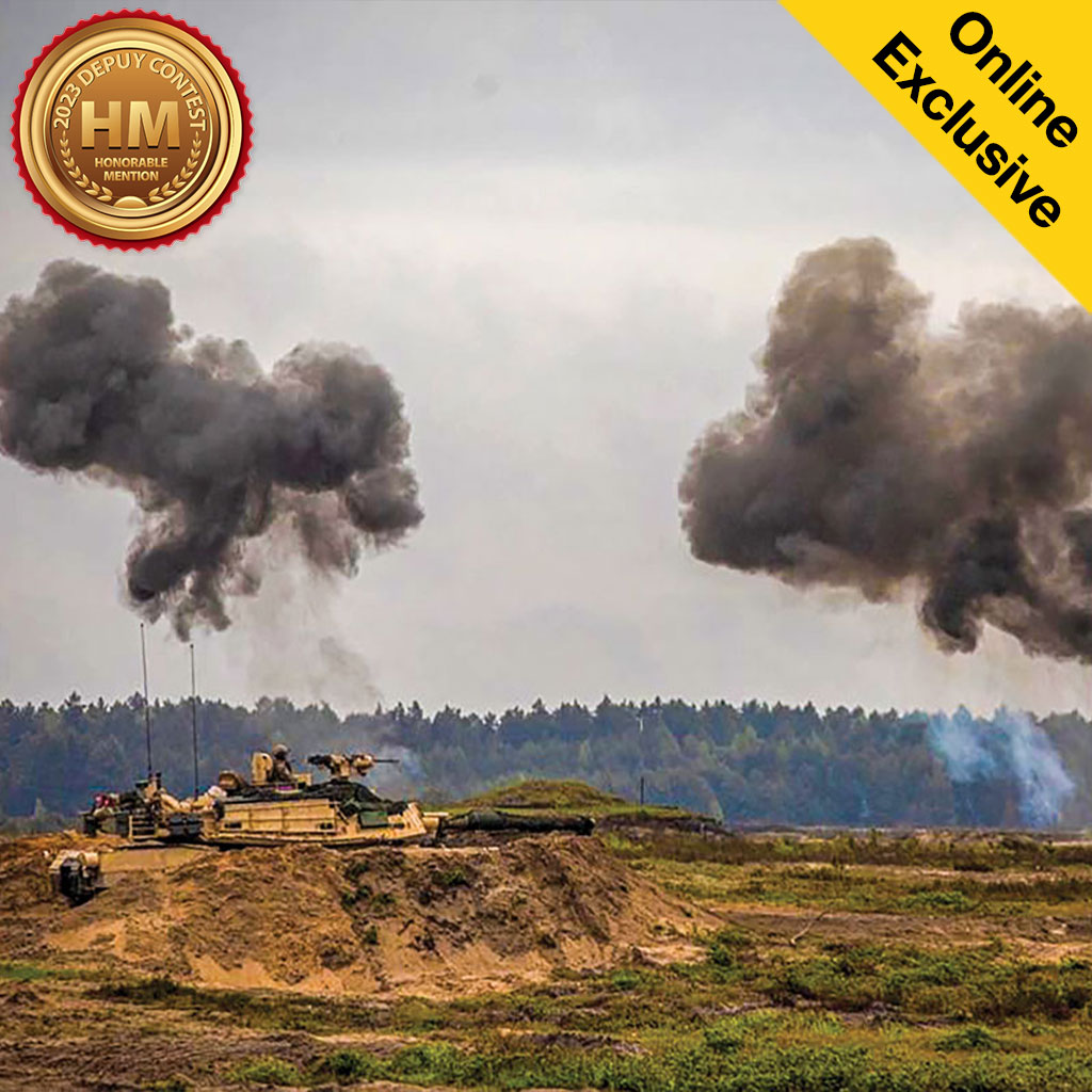 Military tank firing on a field with large plumes of smoke rising into the air, featuring a badge in the corner stating Online Exclusive.