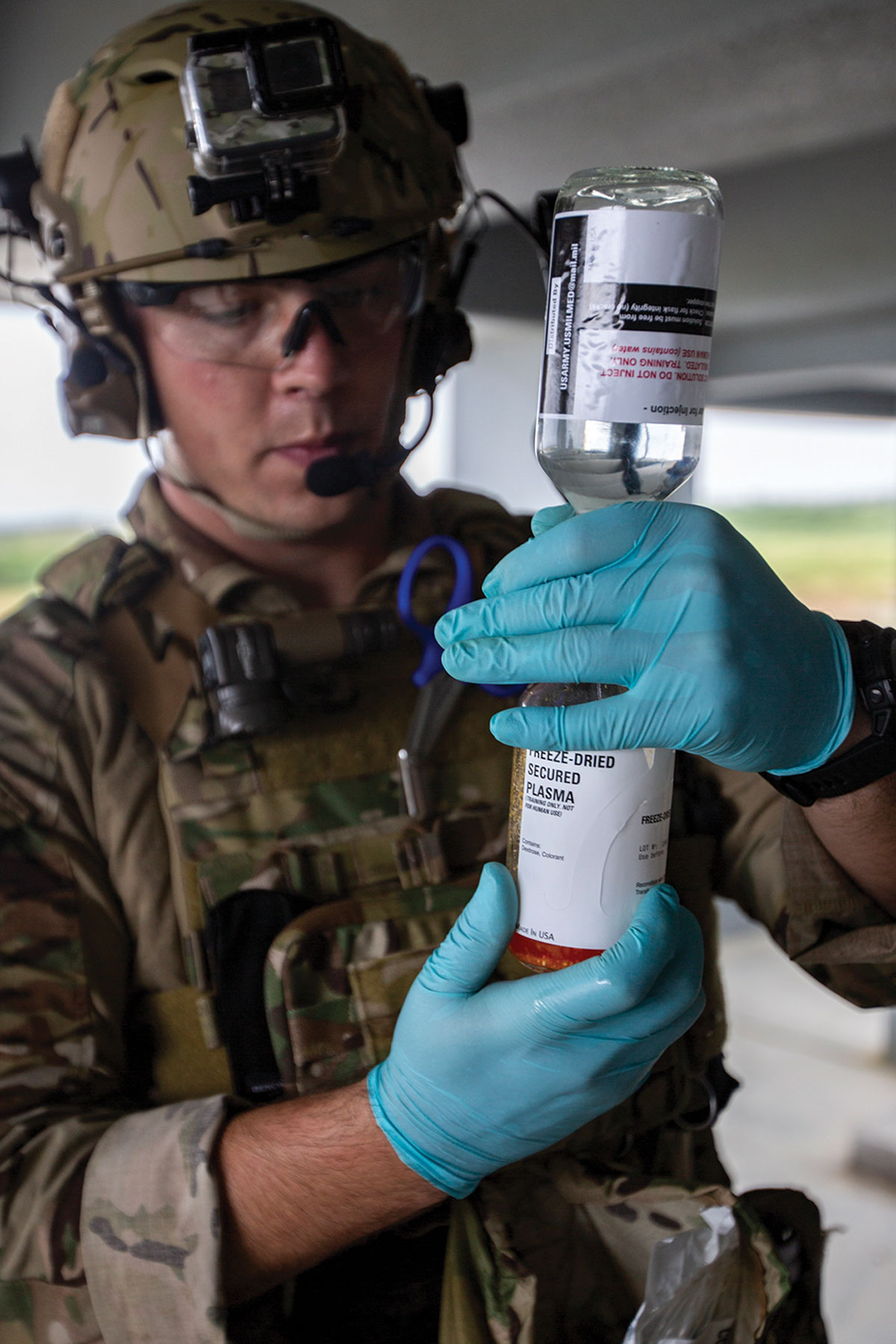 An airman with Special Operations Forces Medical Element, 18th Wing in military gear prepares freeze-dried plasma, ready for a medical emergency.