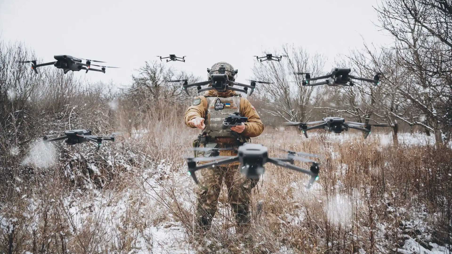 Soldier operating multiple quadcopter drones over a snowy field