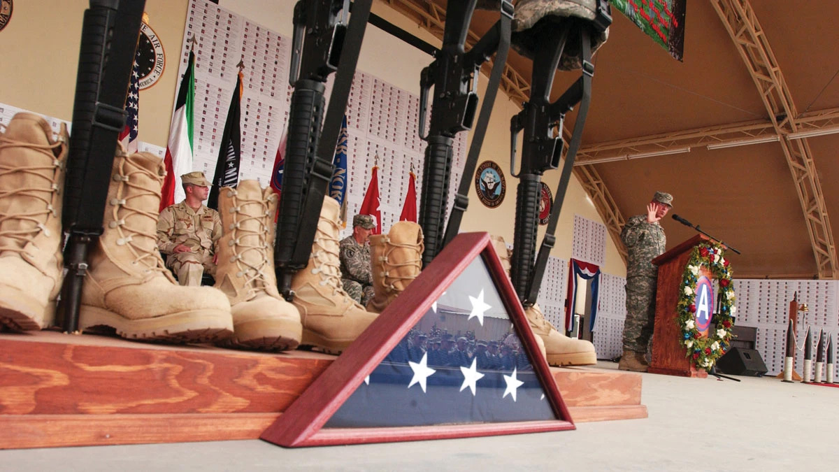 Lt. Gen. Jim Lovelace, U.S. Army Central commanding general, addresses the crowd of service members, civilians, coalition forces troops as well as Kuwaiti soldiers during a Memorial Day observance at Camp Buehring, Kuwait, 26 May 2008. More than four thousand service members are pictured on the wall behind Lovelace, which commemorates the sacrifices of those who have fallen during Operations Iraqi Freedom and Enduring Freedom.