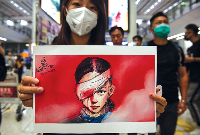 A woman holds a drawing depicting an injured protester