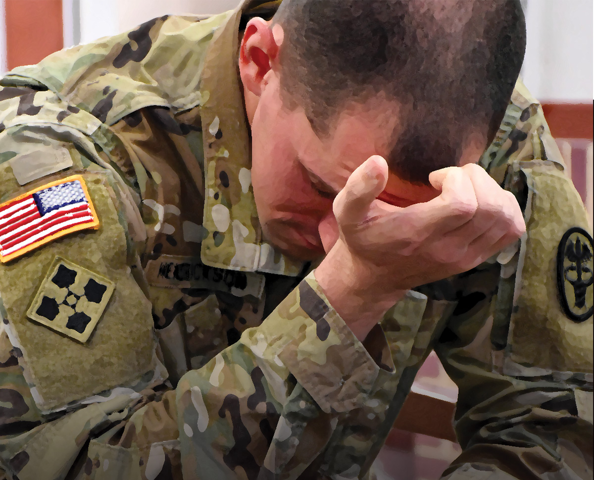 A photo of a stressed soldier sitting with his right hand covering his face.