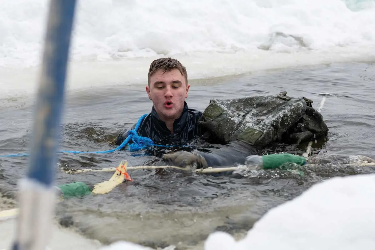 Spc. Adrien Dutter, a forward observer assigned to Company C, 1st Battalion, 24th Infantry Regiment, 1st Brigade Combat Team, out of Fort Wainwright, Alaska, retrieves skiing gear during the polar plunge portion of winter survival training 19 February 2023 at Arctic Forge 2023 on Sodankylä Garrison, Finland.
