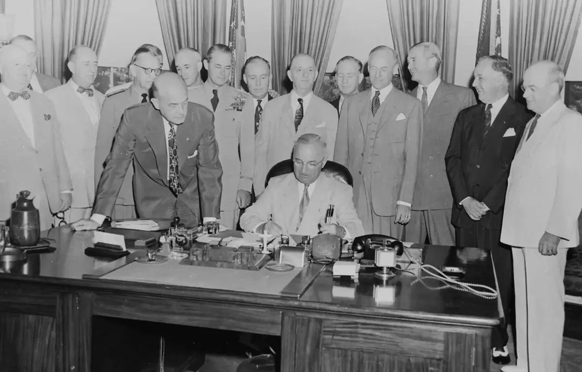 Diversos dignitários testemunham a assinatura pelo Presidente Harry S. Truman