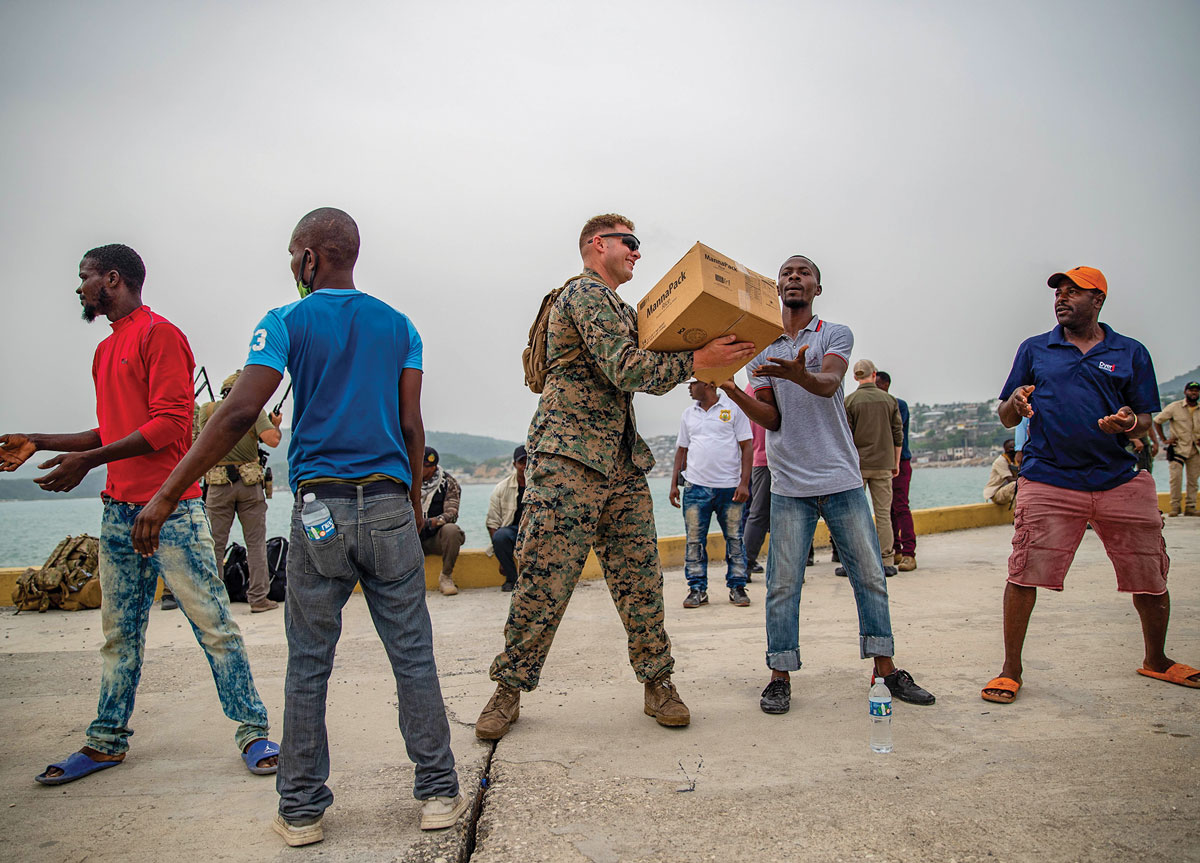 Fuzileiro naval da Força-Tarefa Conjunta–Haiti (JTF-Haiti) e voluntários ajudam a descarregar caixas para redistribuição no Porto de Jérémie, Haiti, em 31 de agosto de 2021