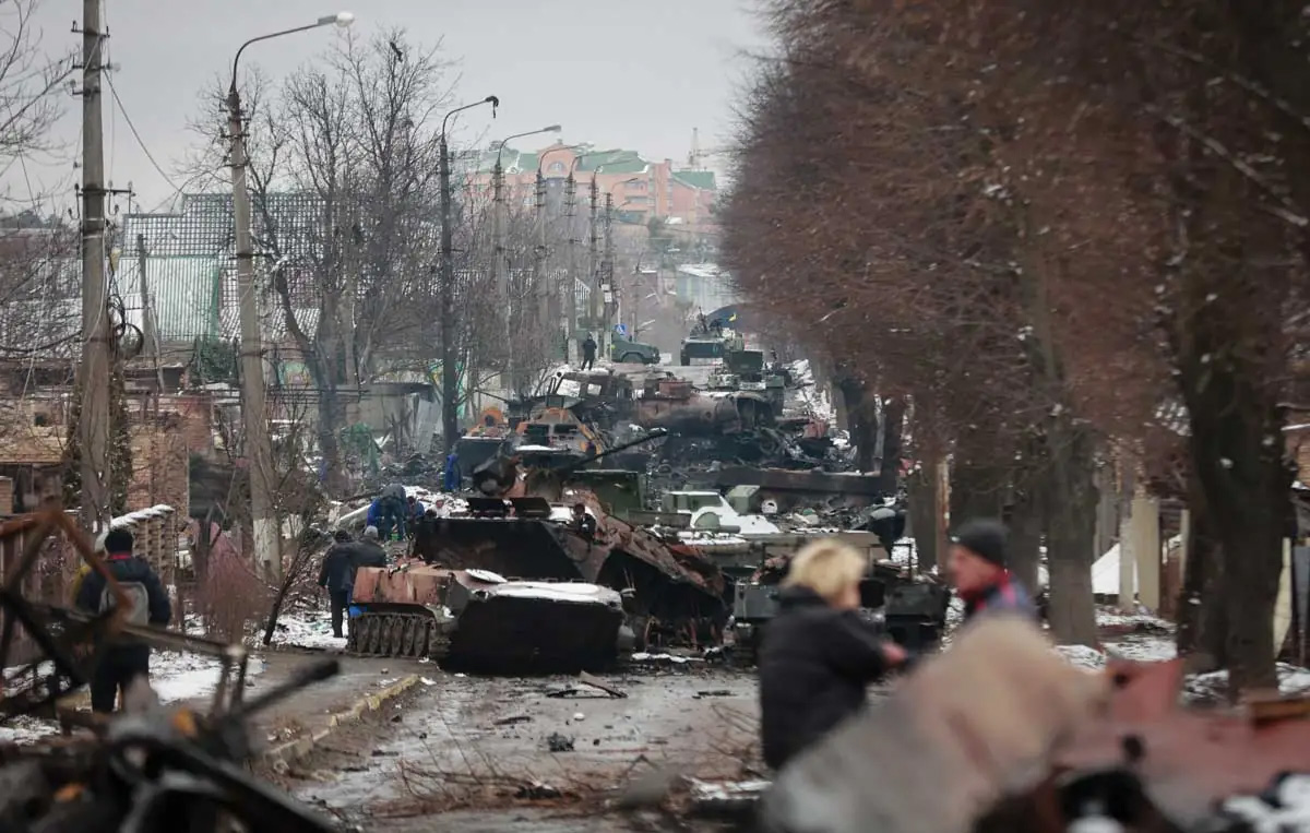 Un grupo de personas observa los restos destruidos de vehículos militares rusos en una carretera de la ciudad de Bucha, cerca de la capital, Kiev, Ucrania, el 1 de marzo de 2022.