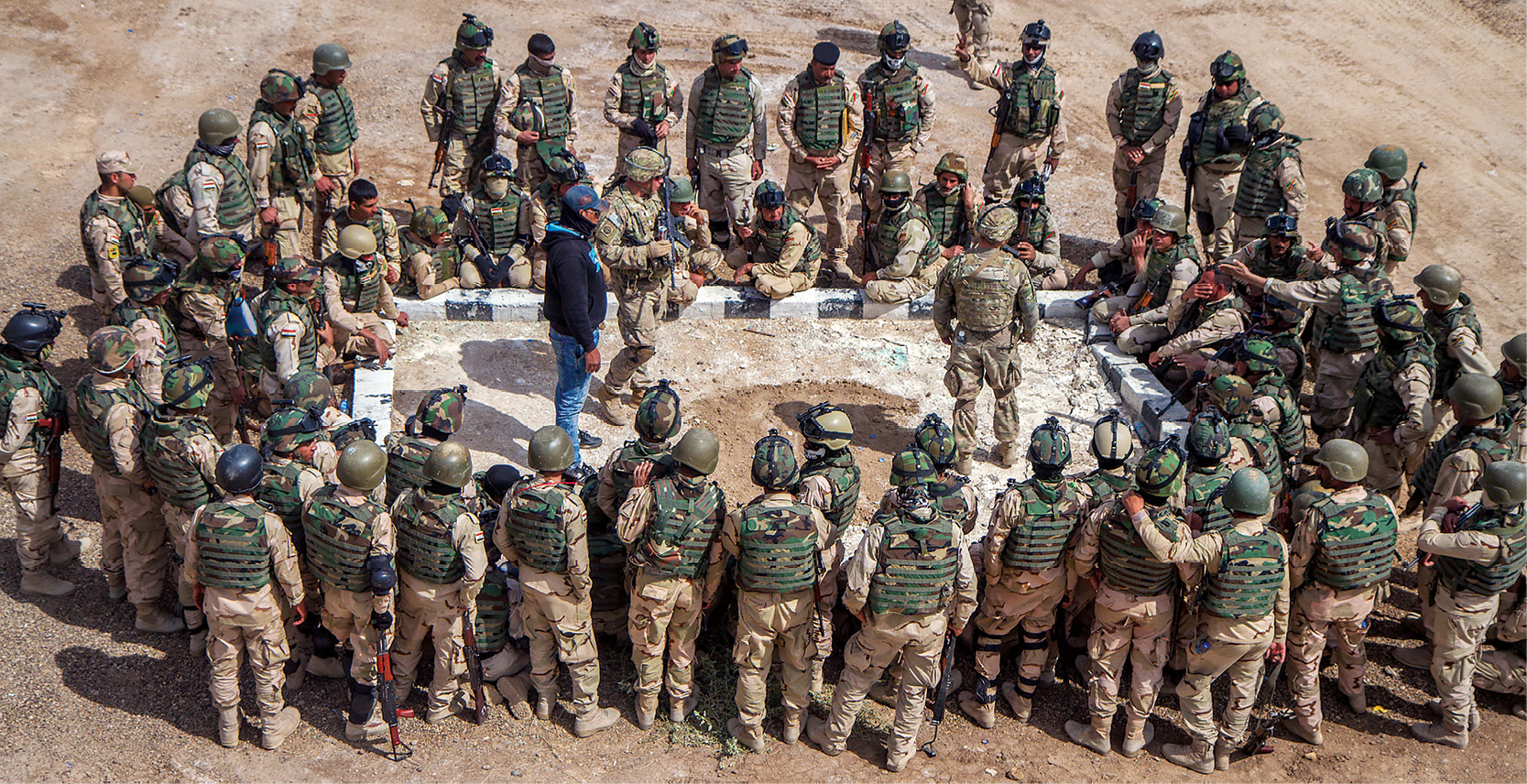 Iraqi army soldiers look on as U.S. soldiers use a sand table to demonstrate how to react to an ambush 24 March 2015 during a training exercise at a training area on Camp Taji, Iraq. (Photo by Sgt. Cody Quinn, U.S. Army)