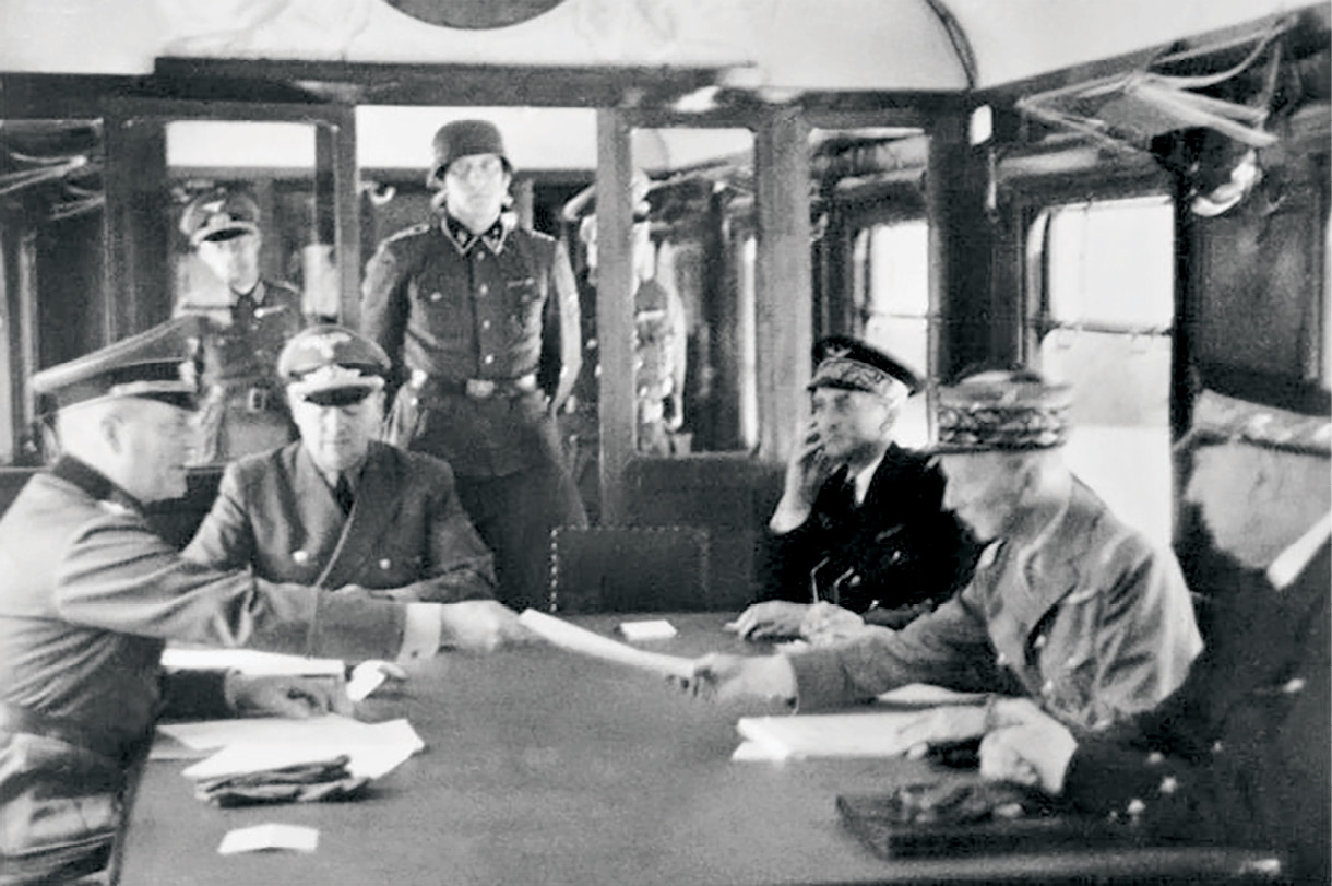 German Gen. Wilhelm Keitel (left) and French Gen. Charles Huntzinger (right center) exchange documents during the signing of the Armistice acknowledging the French Third Republic’s surrender to Nazi Germany 22 June 1940 in the Compiègne Forest, France. In an act of retribution, Adolf Hitler chose the Compiègne Wagon (railcar) and the forest for the signing, the same venue used for Germany’s surrender to end the First World War. Author James Tollefson contends that Germany’s rapid victory over France was the result of a failure by the French to evolve their doctrine during the interwar period. (Photo courtesy of Wikimedia Commons)