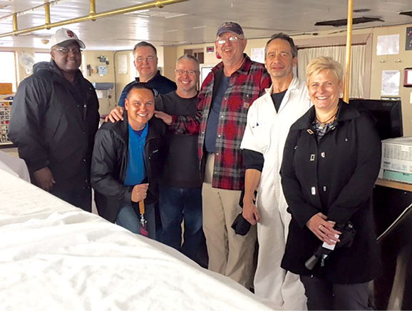 Office of the Secretary of Defense Logistics Program fellows visit the bridge of the USNS Gilliland 28 October 2015 during a tour of the Military Sealift Command (MSC) ship. Shown from left to right are Stanley McMillian, Lt. Col. Ed Hogan (kneeling), Bryan Jerkatis, Donald Gillespie, Art Clark (MSC Surge Sealift Program Readiness Officer), USNS Gilliland’s Master Keith Finnerty, and Renee Hubbard. (Photo courtesy of U.S. Navy)