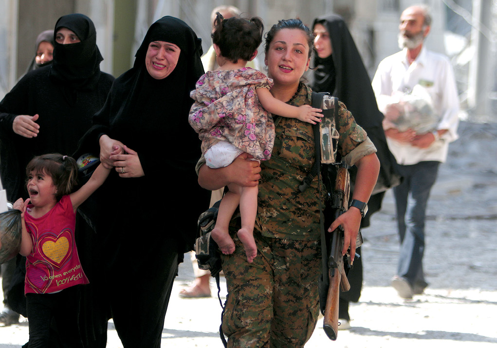 A Syrian Democratic Forces (SDF) fighter helps civilian refugees, including large numbers of  women and children, who were evacuated by the SDF from an Islamic State-controlled neighborhood of Manbij 12 August 2016 in Aleppo Governorate, Syria. The SDF said the Islamic State was using civilians as human shields. (Photo by Rodi Said, Reuters)
