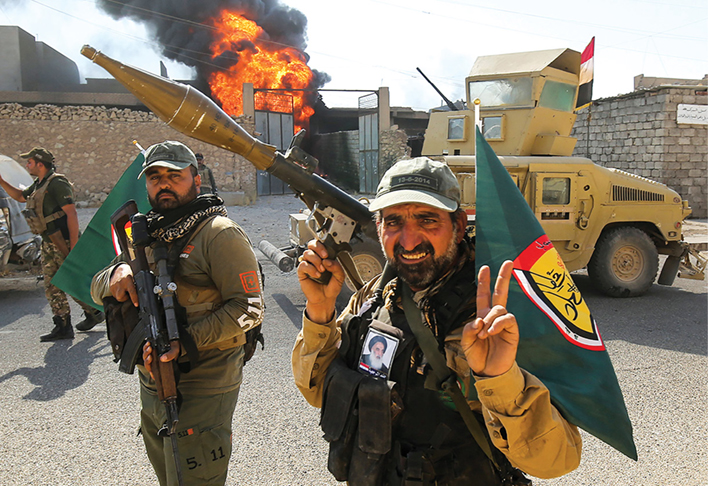 Fighters of Hashed Al-Shaabi (popular mobilization units) flash the victory gesture as they advance through the town of Tal Afar