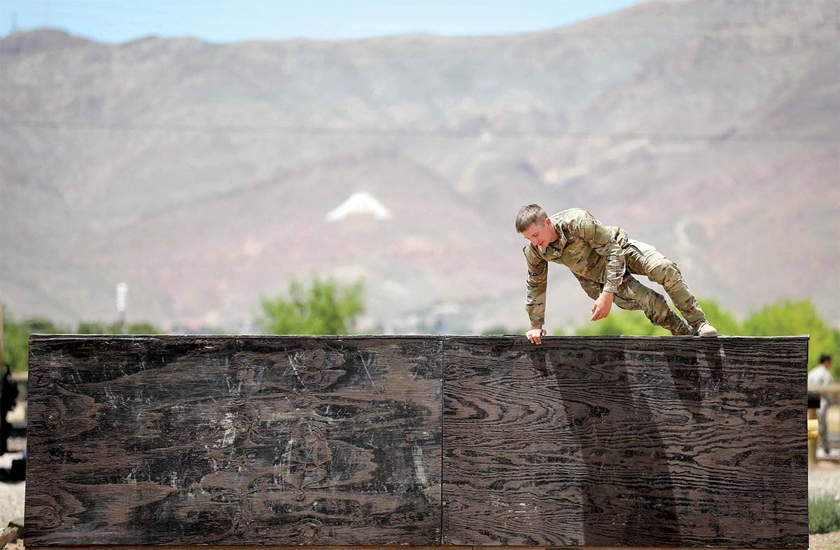 Spc. Gage Paraschos scales a wooden barrier 15 May 2020 during the obstacle course event of the 1st Armored Division Best Warrior Competition at Fort Bliss, Texas.
