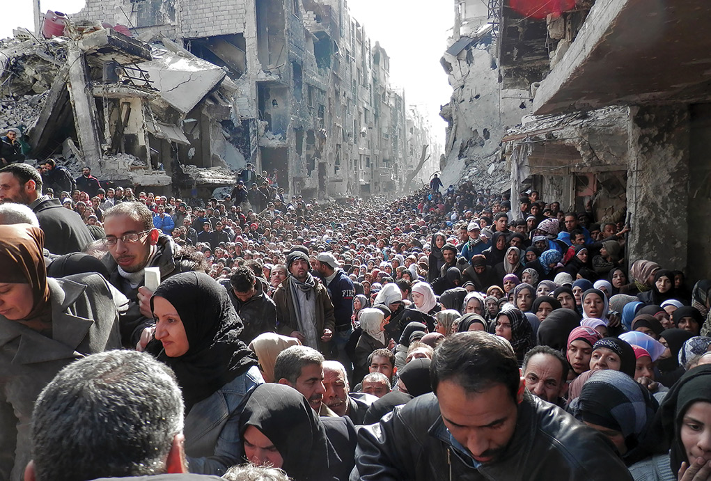 Thousands of desperate residents flood a destroyed main street January 2014 in Damascus, Syria, to meet aid workers from the United Nations Relief and Works Agency (UNRWA). The UNRWA was able to complete its first humanitarian food distribution in Yarmouk Camp there after almost six months of siege. (Photo courtesy of UNRWA)