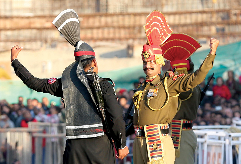 Um comandos paquistanês (à esquerda) e um soldado indiano gesticulam, um ao outro, durante uma cerimônia de arreamento de bandeiras, em Wagah, um vilarejo fronteiriço entre os dois países, perto de Lahore, a capital da Província de Punjab, 9 Jan 17. Essa dramática cerimônia acontece todos os dias e atrai muitos visitantes de ambas as nações. (Liu Tian/Xinhua/Alamy Live News)