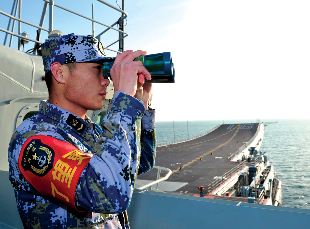 Militar da MELP a bordo do Liaoning, primeiro navio-aeródromo chinês, durante sua visita a um porto militar por volta de 2013, no Mar do Sul da China, em Sanya, Província de Hainan, China. (Foto de Hu Kaibing, Xinhua)