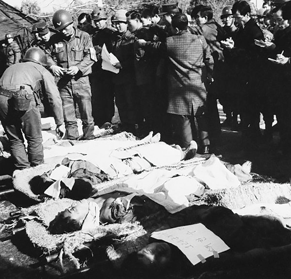 Militares norte-americanos e sul-coreanos inspecionam os corpos de agentes infiltrados das forças especiais norte-coreanas, mortos durante a operação “Casa Azul” [nome da residência presidencial em Seul], em janeiro de 1968, na qual tentaram assassinar o Presidente sul-coreano Park Chung-hee. (Foto de Korean Newsletter, https://president.jp/articles/-/23398)