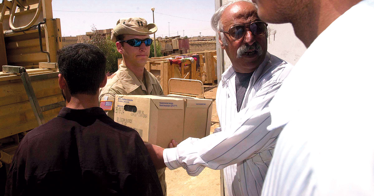 Oficial de Assuntos Civis do 96o Batalhão de Assuntos Civis entrega cloreto de sódio a um funcionário do Hospital de Pediatria e Maternidade em Najaf, no Iraque, 22 Abr 2003. (Foto do 2o Sgt Kyle Davis, Exército dos EUA)