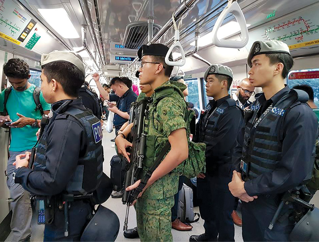 Militares cingapurianos juntos com uma patrulha policial a bordo de um trem subterrâneo. Os militares do Serviço Nacional fazem contribuições significativas para a defesa, como a melhoria das operações de segurança doméstica. (Foto cortesia das Forças Armadas de Cingapura)