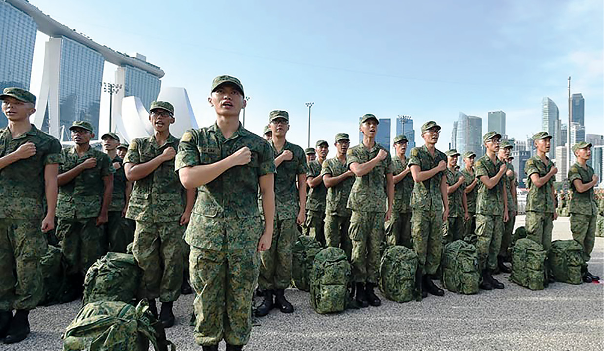 Recrutas recitam o juramento às Forças Armadas de Cingapura durante a solenidade de conclusão da Instrução Militar Básica na Marina Bay Floating Platform no centro metropolitano de Cingapura, 12 Dez 15. A silhueta da cidade e as famílias animadas são lembranças visuais do que os recrutas têm jurado proteger. (Foto cortesia das Forças Armadas de Cingapura)
