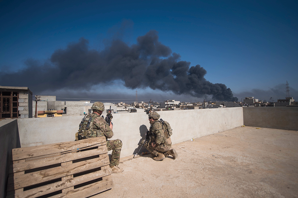 Militares da 82<sup>a</sup> Divisão Aeroterrestre, componentes da Força-Tarefa Conjunta Combinada—Operação <em>Inherent Resolve</em>, utilizam um terraço como posto de observação, durante os combates travados em Mossul, Iraque, 07 Mar 17. (Sgt Alex Manne, Exército dos EUA)