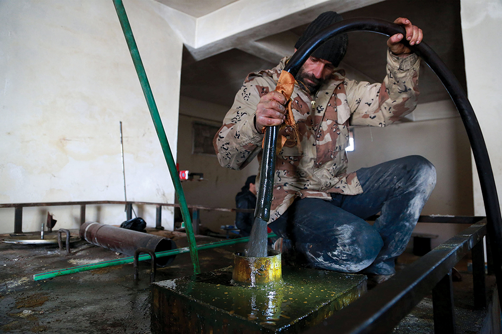 Um homem coloca petróleo bruto em um tanque dentro de uma refinaria improvisada na zona rural nos arredores de Aleppo, Síria, 13 Jan 15. Desde o início de sua expansão territorial sobre partes da Síria e do Iraque, o Estado Islâmico (EI) financiou suas atividades, sobretudo, com a extração e refino de petróleo proveniente das áreas produtoras de petróleo que tinha capturado, vendendo-o no comércio local ou exportando-o através da fronteira turca para compradores internacionais. Os proventos foram utilizados para apoiar ações militares e administrar os territórios incorporados ao novo califado. Como resultado, tanto forças russas quanto norte-americanas priorizaram ataques contra as refinarias de petróleo e os comboios de combustível, bem como contra os gabinetes financeiros do EI, a fim de degradar a capacidade do grupo de se autossustentar financeiramente. (Foto por Nour Kelze, Reuters)