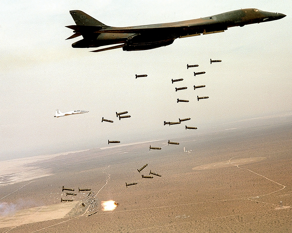 Um bombardeiro B-1B Lancer lança munições cluster, 05 Nov 02. Bombas de fragmentação como essas abrem-se no ar e liberam várias submunições explosivas que são eficazes contra uma área-alvo, como formações de tropas, colunas de viaturas, campos de pouso, instalações de comando e controle e concentrações logísticas. (Foto cedida pela Força Aérea dos EUA)