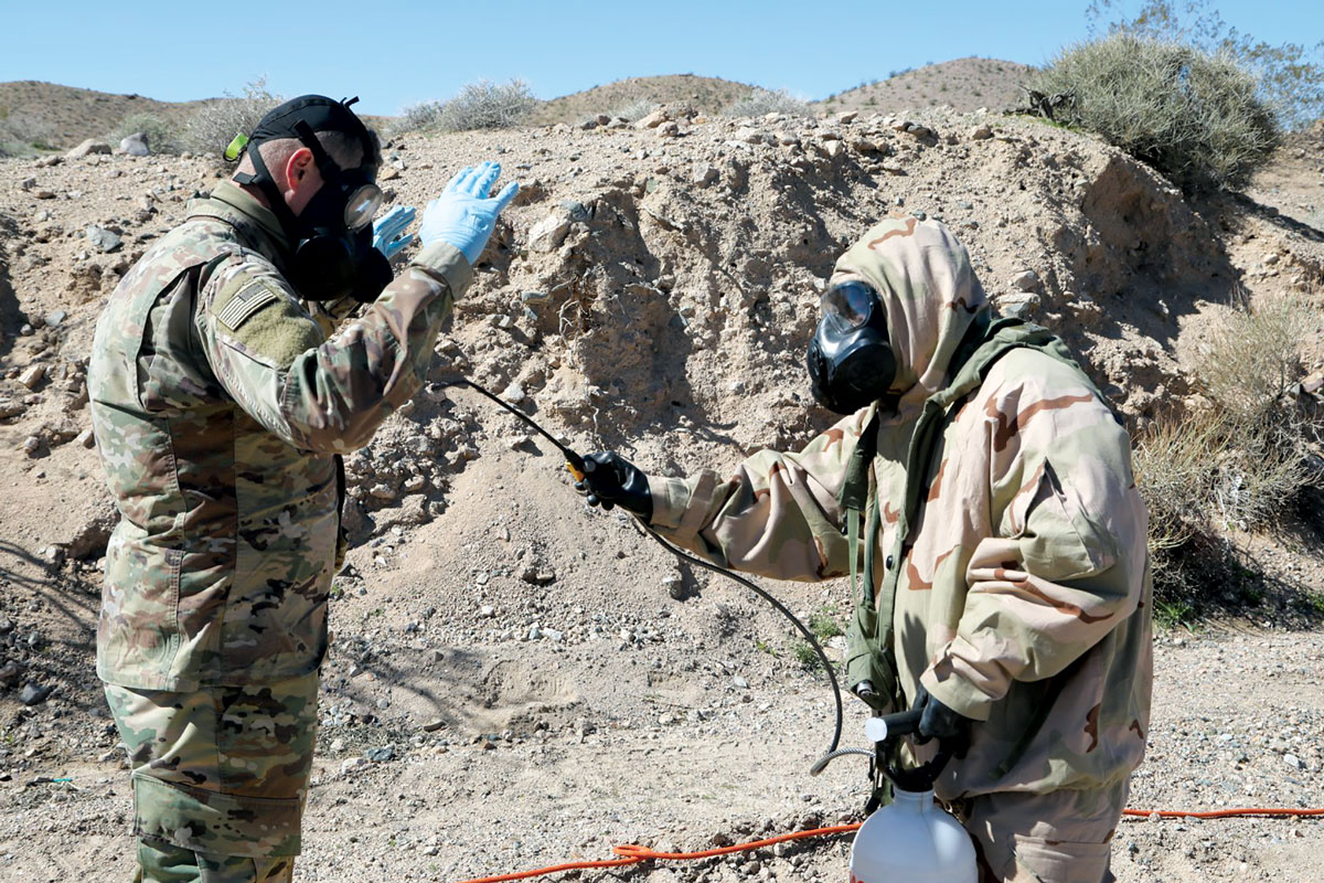 Integrante da 44a Companhia DQBRNE borrifa água em outro soldado, que foi exposto a um agente químico simulado em um posto de descontaminação durante um rodízio de treinamento no Centro Nacional de Treinamento, Forte Irwin, Califórnia, 13 Mar 2019. (Foto de Clemens Gaines, Com Soc, 20o Comando DQBRNE)