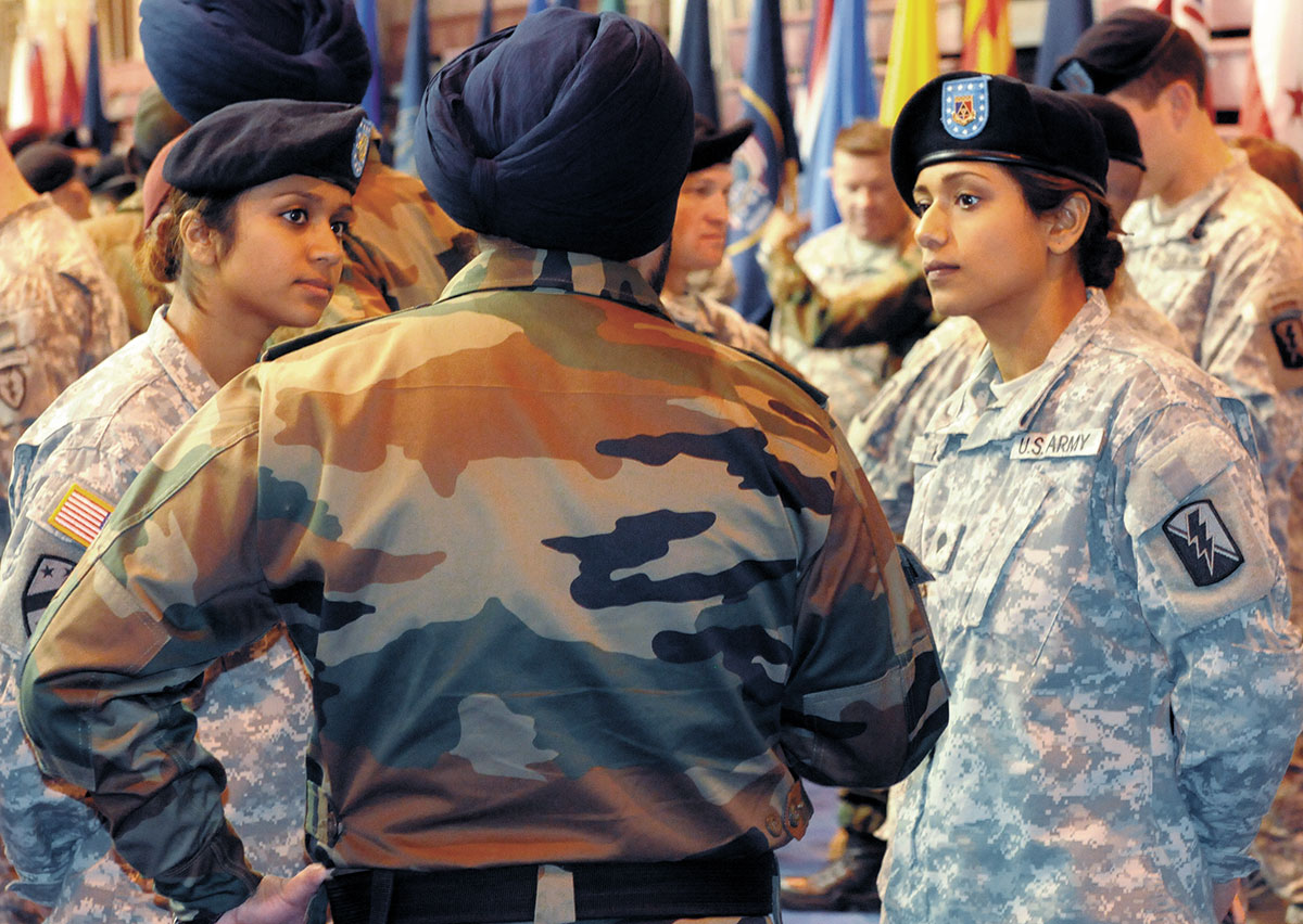 La cabo Balreet Kaur y la especialista Jasleen Kaur, hermanas nacidas en India, comparan cortesías comunes de Estados Unidos e India con un soldado hindú antes de la ceremonia de apertura del ejercicio de adiestramiento conjunto Yudh Abyhas 2010 en la Base Conjunta Elmendorf-Richardson, estado de Alaska, 31 de octubre de 2010. Las hermanas son integrantes de la Guardia Nacional del estado de California en el 79º Equipo de combate de brigada de infantería. Las dos son enfermeras y fueron enlaces culturales durante el ejercicio de dos semanas. (Foto: Ejército de EUA, Especialista Ashley M. Armstrong)