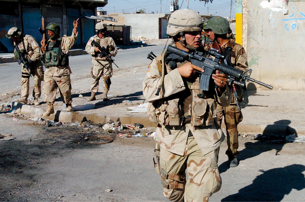 Soldados del Ejército de EUA del 3er Regimiento de Caballería Blindada y soldados iraquíes cruzan una intersección durante una patrulla de seguridad rutinaria en el centro de Tal Afar, Irak, 11 de septiembre de 2005. El propósito de estas patrullas fue perturbar los refugios insurgentes y despejar los escondites de armas en el área de operaciones. (Foto: Armada de EUA, 1er Maestre Alan D. Monyelle)
