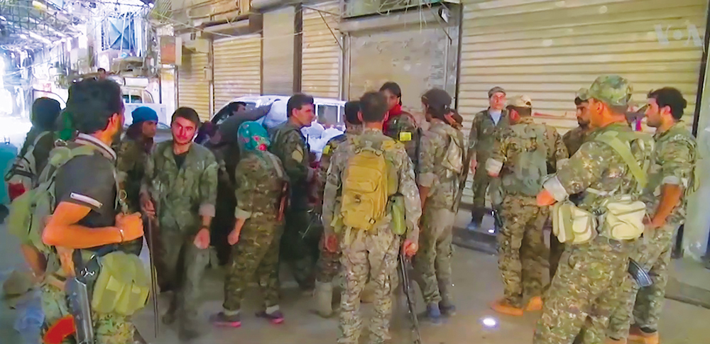 Integrantes de las Fuerzas Democráticas Sirias discuten operaciones en la ciudad siria de Manbij poco después de un combate feroz para liberarla del control del Estado Islámico, 12 de agosto de 2016. (Captura de pantalla, Voz de América)