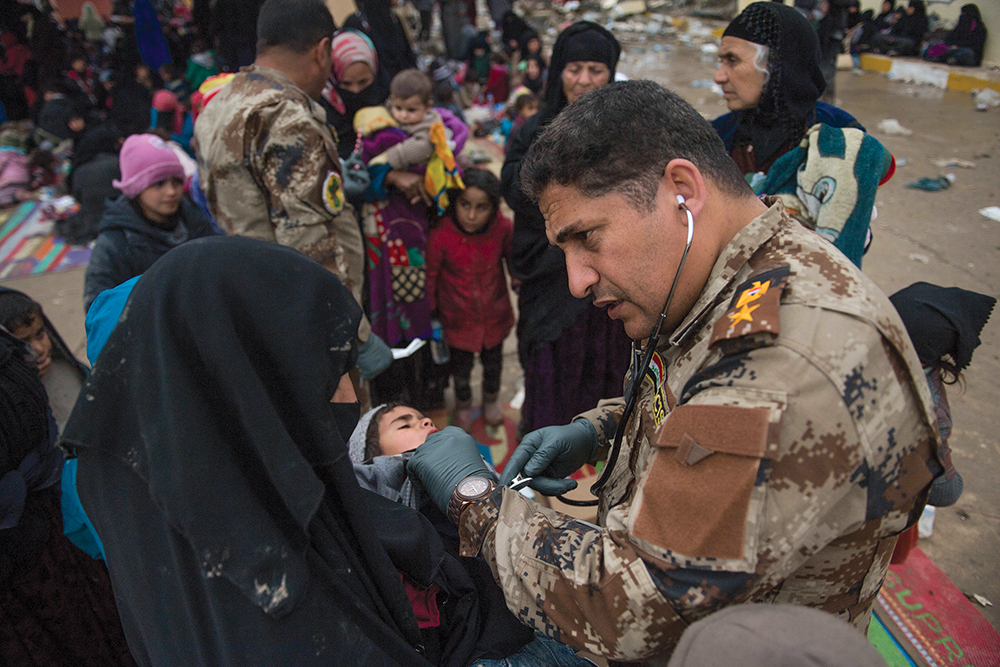 El teniente coronel cirujano Hayder al-Sudani, del Servicio Antiterrorista iraquí, atiende a una niña en una estación de procesamiento para personas desplazadas internamente el 3 de marzo de 2017 cerca de Mosul, Iraq. (Foto: Sargento 2o Alex Manne, Ejército de Estados Unidos)