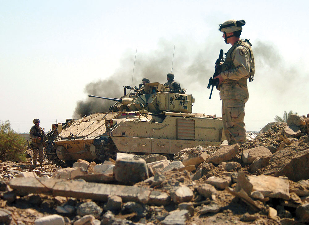 Soldados del 2o Batallón, 11o Regimiento de Caballería Blindada, apoyados por un vehículo de combate Bradley, avanzan hacia un búnker durante una incursión en el Complejo de Armas de Hateen en Babil, Iraq, 26 de marzo de 2005. (Foto: Departamento de Defensa)