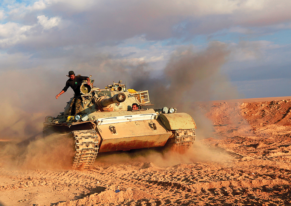 Combatientes de las Fuerzas de Movilización Populares (en su mayor parte milicia chiita iraquí) viajan en un tanque en al-Qaim, Iraq, cerca de la frontera con Siria, 26 de noviembre de 2016. (Foto: Alaa al-Marjani, Reuters)