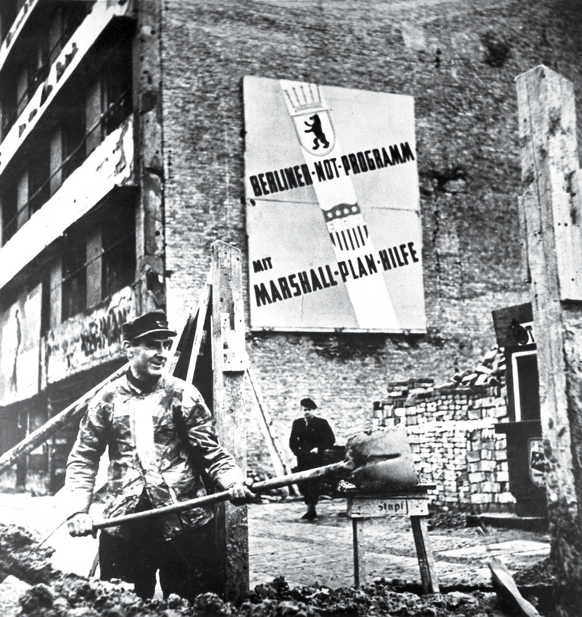 Un trabajador alemán palea escombros en 1949 como parte de los esfuerzos de construcción en Berlín Occidental, Alemania. El letrero dice, «El Programa de Emergencia de Berlín con el apoyo del Plan Marshall». El apoyo brindado a Alemania por el Plan Marshall fue de unos US$ 1 390 600 y permitió que el país resurgiera de las cenizas de la derrota, como quedó simbolizado por este trabajador de Berlín Occidental. Un año antes del Plan Marshall en 1951, Alemania había superado su nivel de producción antes de la guerra. (Foto: National Archives)