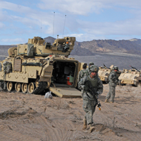 Soldados del 2o Equipo de Combate en el nivel de Brigada, 1a División de Infantería, del Fuerte Riley, Kan., cerca de sus vehículos de combate Bradley, en el entrenamiento nacional en el Fuerte Irwin, estado de California, 20 de febrero de 2013. (David Vergun, Army News Service)