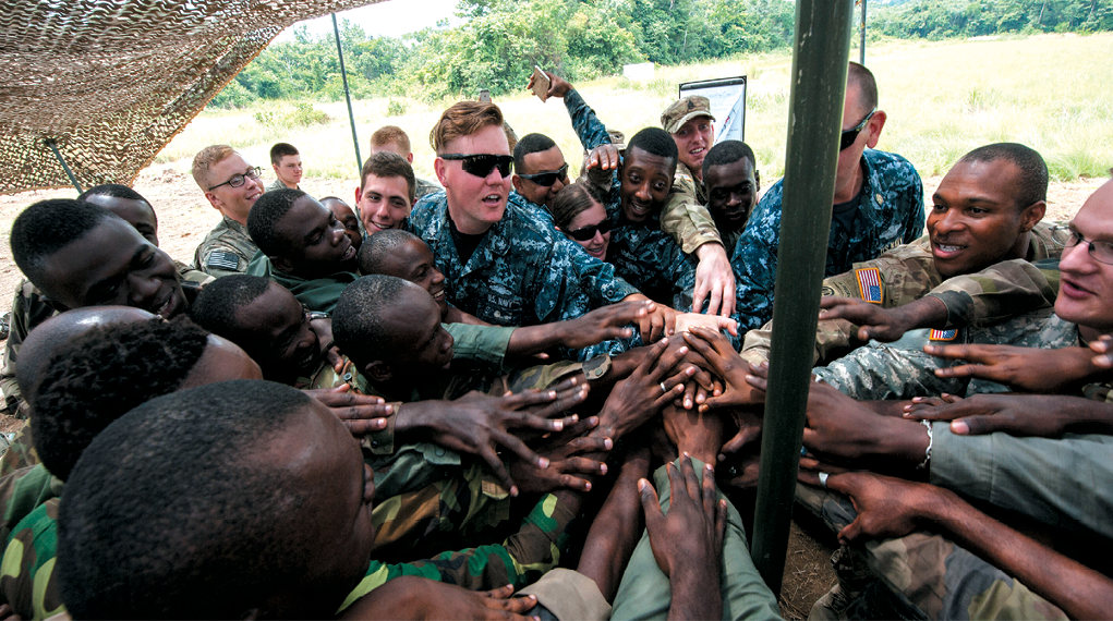 Integrantes de las Fuerzas Armadas de EUA del Instituto de Apresto Médico de Defensa e infantes de marina del 3er Batallón, 7o Regimiento de infantería, 2o Equipo de combate de brigada, 3a División de infantería juntos con los soldados de las Fuerzas Armadas gabonesas en una reunión durante un curso táctico de cuidado de bajas de combate mientras participaban en el ejercicio Central Accord 2016, en Libreville, Gabon, 17 de junio de 2016. El Comando de Estado Unidos en África conduce el ejercicio anualmente con socios conjuntos y multinacionales para practicar y demostrar destreza en la conducción de operaciones de paz. (Foto cortesía del sargento Brian Kimball, Comando de Estado Unidos en África)