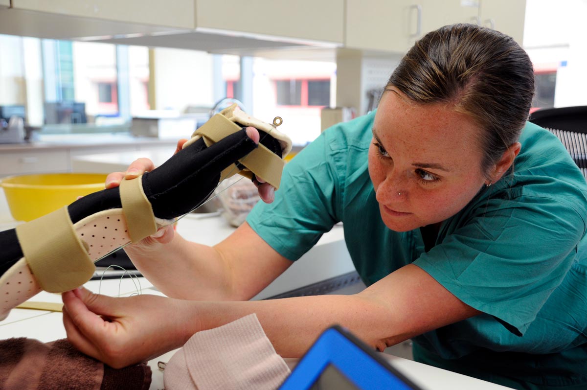 >Jennifer Tucker, an occupational therapist, adds a component to a patient’s splint to gradually stretch the tendons in his hand.