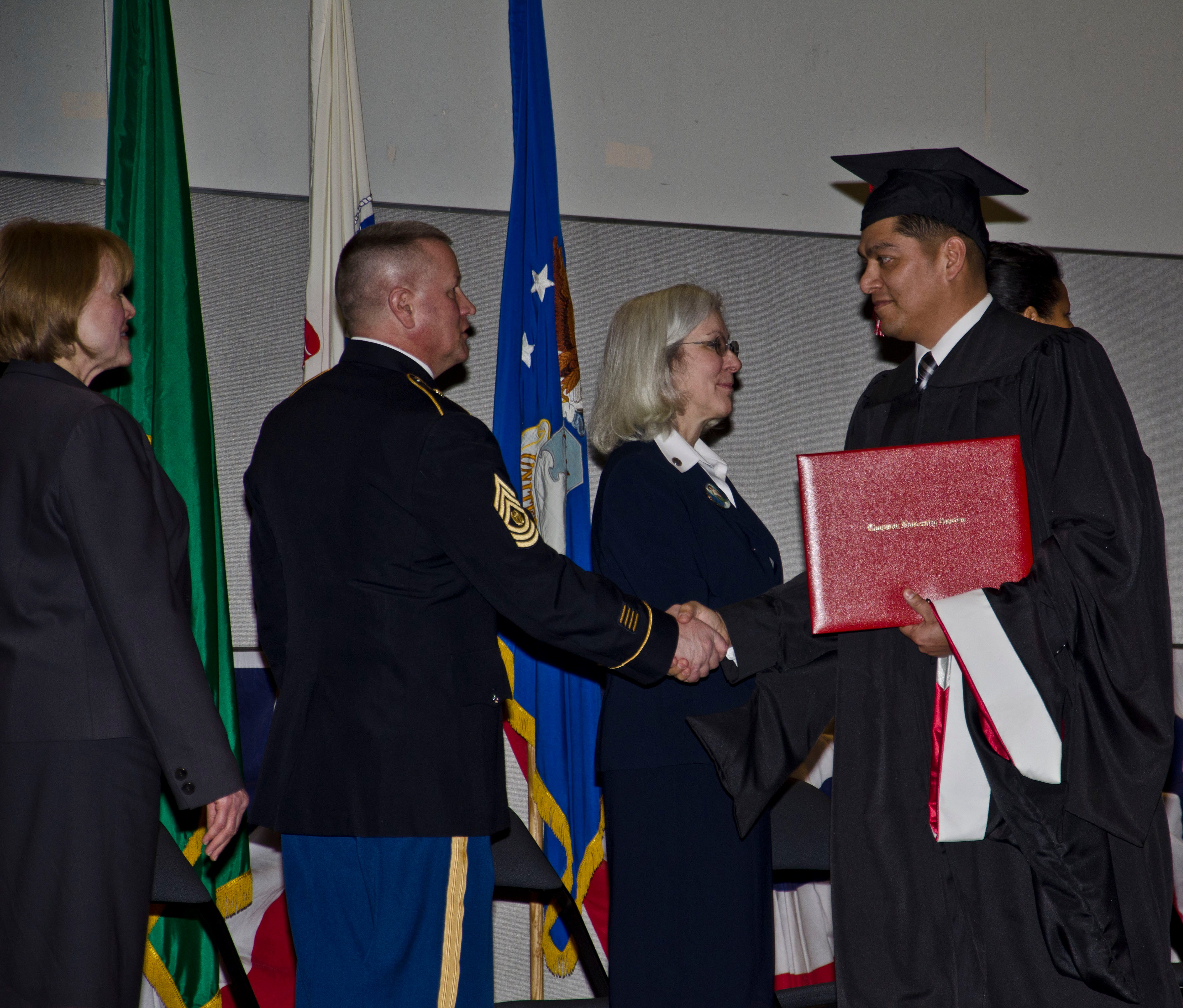 Master Sgt. Ramiro R Cantu is presented his master's degree during the first combined college graduation ceremony for Joint Base Lewis-McChord
