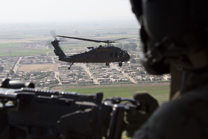A U.S. Army UH-60 Blackhawk door gunner watches as another UH-60 Blackhawk flies over Syria during a visit by Special Presidential Envoy