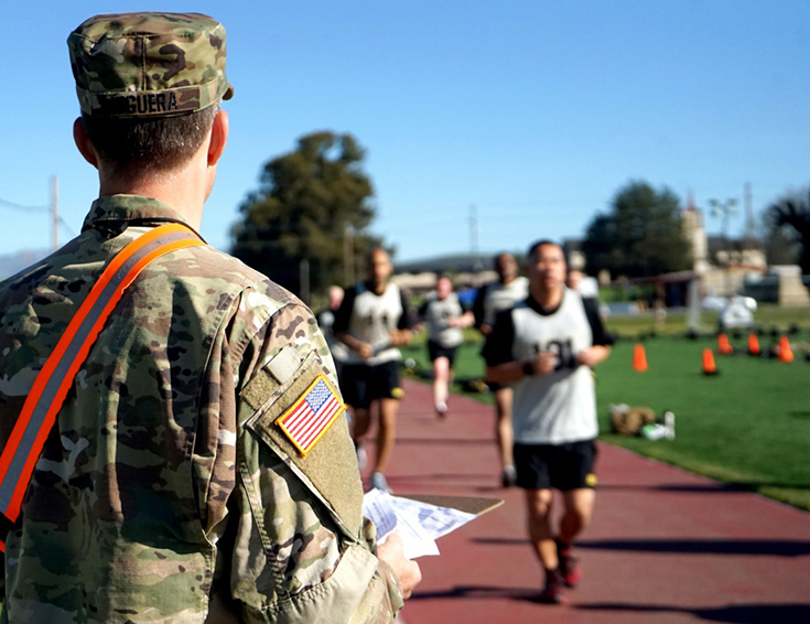 A grader keeps track of laps while Soldiers from the 223rd Military Intelligence Battalion perform a two-mile run during an Army Combat Fitness Test