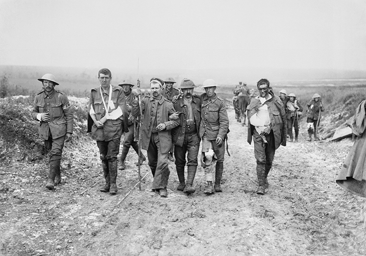 A German prisoner helps British wounded make their way to a dressing station