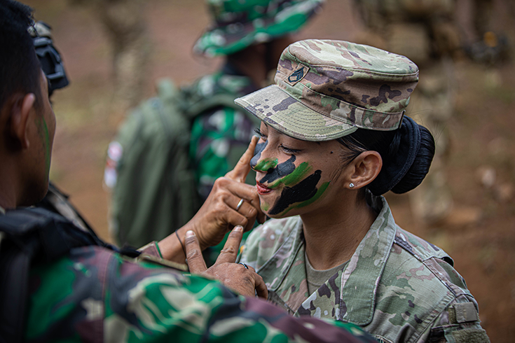 Staff Sgt. Annora Borja, Logistics Advisor, Maneuver Advisor Team 5211, gets a lesson on Indonesian camouflage techniques from the Tentara Nasional Indonesia Angkatan Darat